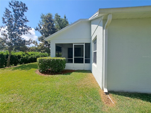 view of home's exterior featuring a lawn and a sunroom