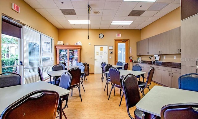 dining room featuring a paneled ceiling, light hardwood / wood-style floors, and sink