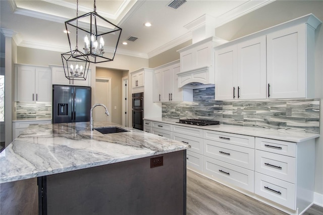 kitchen featuring light hardwood / wood-style flooring, backsplash, an island with sink, sink, and refrigerator with ice dispenser