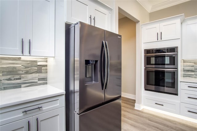 kitchen featuring appliances with stainless steel finishes, crown molding, tasteful backsplash, and light hardwood / wood-style flooring