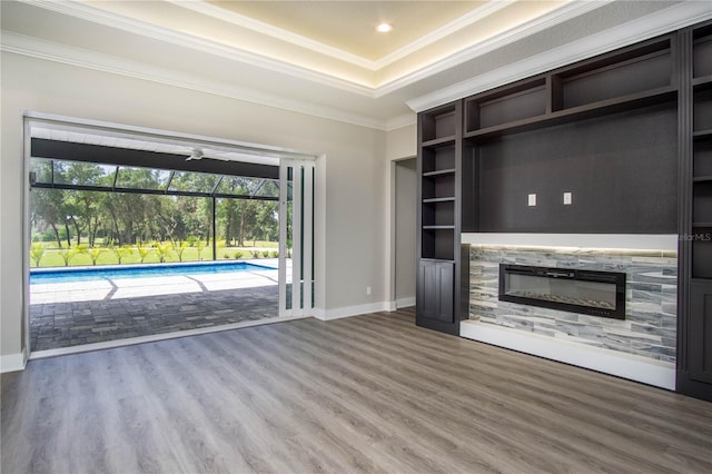 unfurnished living room featuring hardwood / wood-style floors, ornamental molding, and a tray ceiling