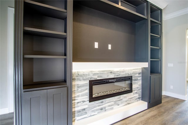 unfurnished living room featuring hardwood / wood-style floors, built in shelves, and crown molding