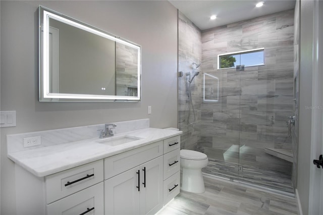 bathroom featuring a shower with shower door, oversized vanity, and toilet