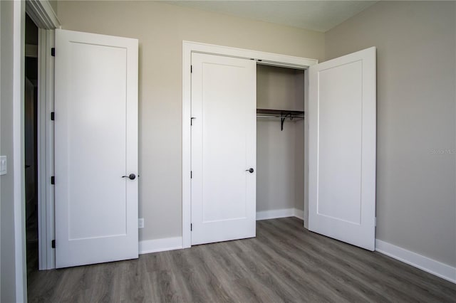 unfurnished bedroom with dark hardwood / wood-style floors and a closet