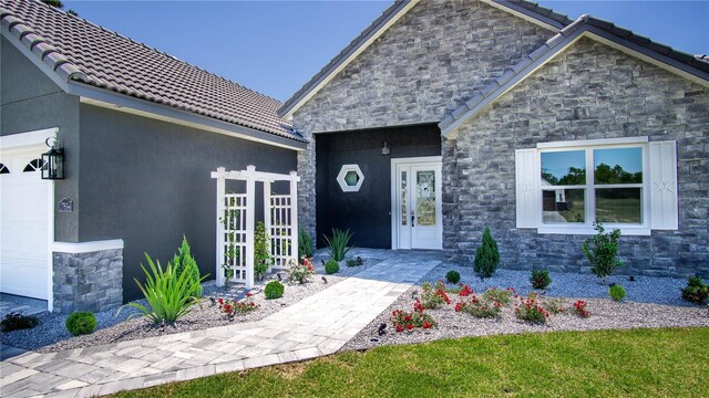 17694 SW 61st Lane Rd, Dunnellon, FL 34432 - property entrance featuring stone siding, an attached garage, and a tile roof