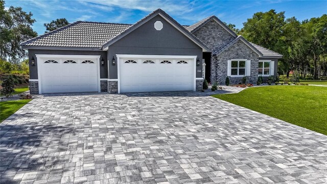 17694 SW 61st Lane Rd, Dunnellon, FL 34432 - view of front of house featuring stone siding, decorative driveway, a front yard, an attached garage, and stucco siding