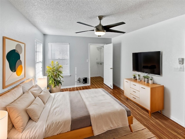 bedroom with hardwood / wood-style flooring, ceiling fan, and a textured ceiling