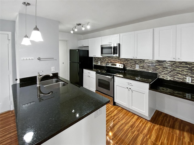 kitchen with appliances with stainless steel finishes, sink, dark stone countertops, white cabinetry, and hanging light fixtures