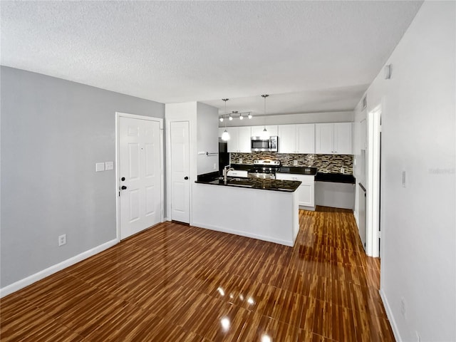 kitchen featuring backsplash, dark wood-type flooring, hanging light fixtures, appliances with stainless steel finishes, and white cabinetry