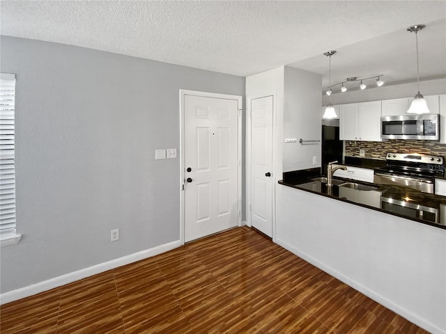 kitchen featuring stainless steel appliances, white cabinetry, hanging light fixtures, and dark wood-type flooring