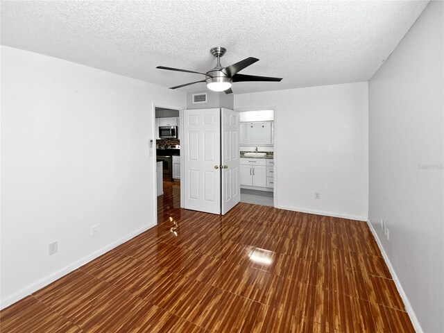 interior space featuring ceiling fan, dark hardwood / wood-style flooring, and a textured ceiling