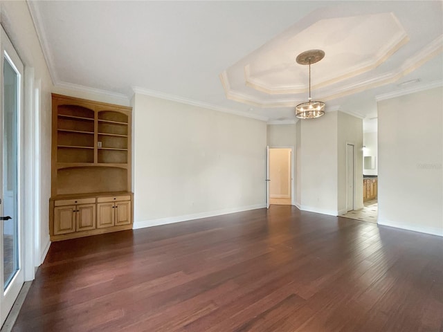 unfurnished living room with built in features, ornamental molding, a tray ceiling, dark hardwood / wood-style flooring, and a chandelier