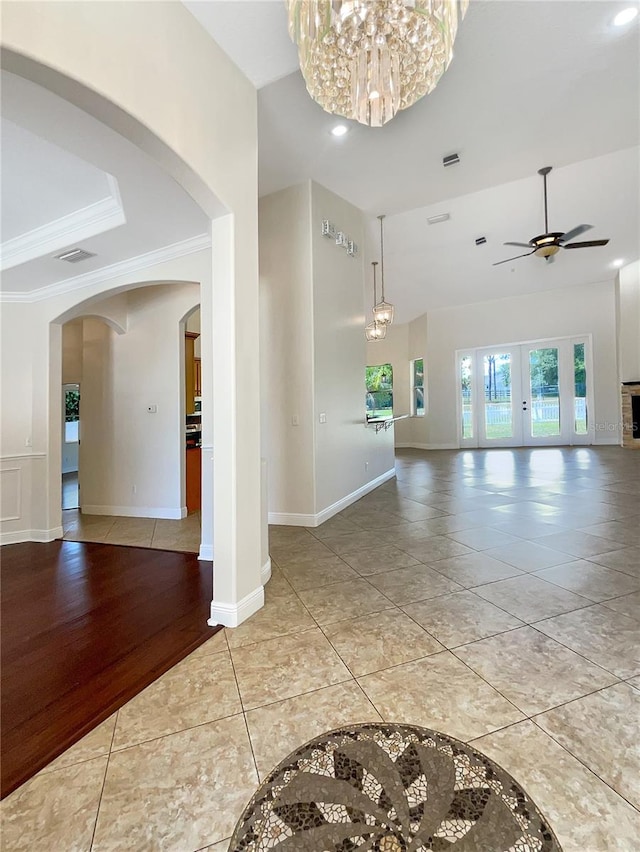 interior space featuring hardwood / wood-style floors, ceiling fan with notable chandelier, french doors, and ornamental molding