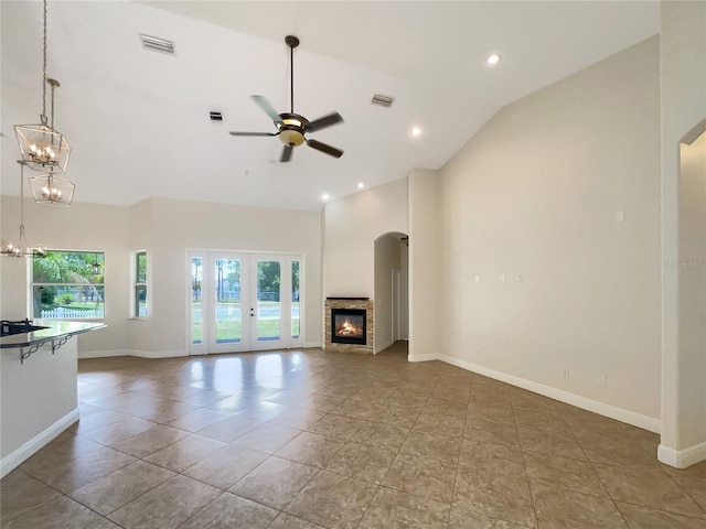 unfurnished living room featuring french doors, tile patterned floors, ceiling fan, high vaulted ceiling, and a fireplace