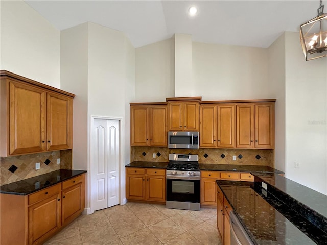 kitchen featuring light tile patterned flooring, dark stone countertops, backsplash, and appliances with stainless steel finishes