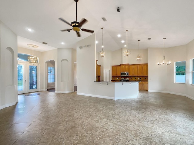 unfurnished living room featuring french doors, high vaulted ceiling, and ceiling fan with notable chandelier