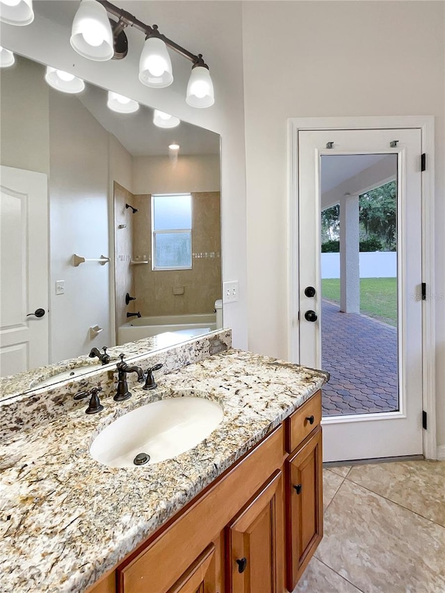 bathroom with tile patterned flooring, vanity, a healthy amount of sunlight, and tiled shower / bath combo