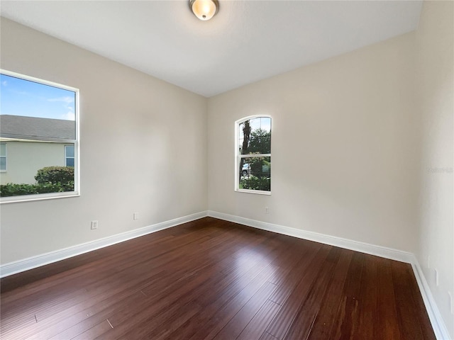 empty room featuring a wealth of natural light and dark wood-type flooring