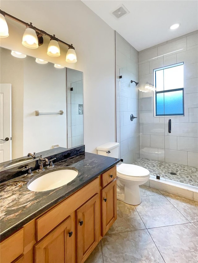 bathroom featuring tile patterned flooring, vanity, a shower with shower door, and toilet