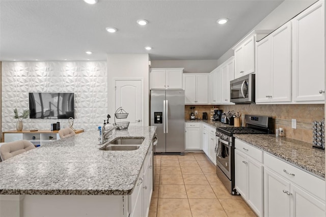 kitchen featuring appliances with stainless steel finishes, white cabinetry, a sink, and backsplash