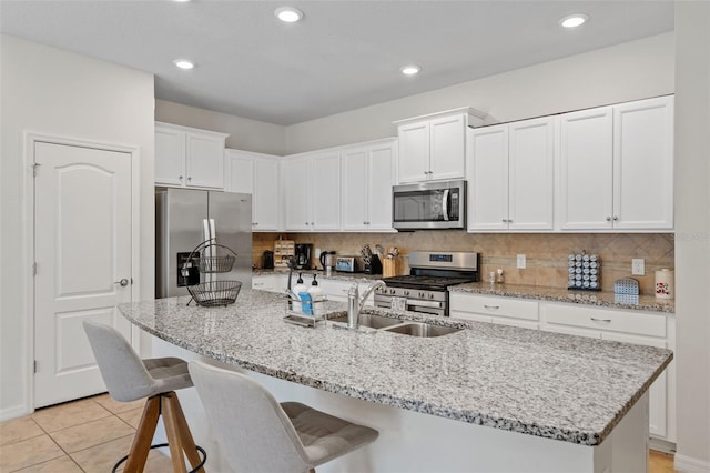 kitchen featuring backsplash, appliances with stainless steel finishes, white cabinets, and a sink