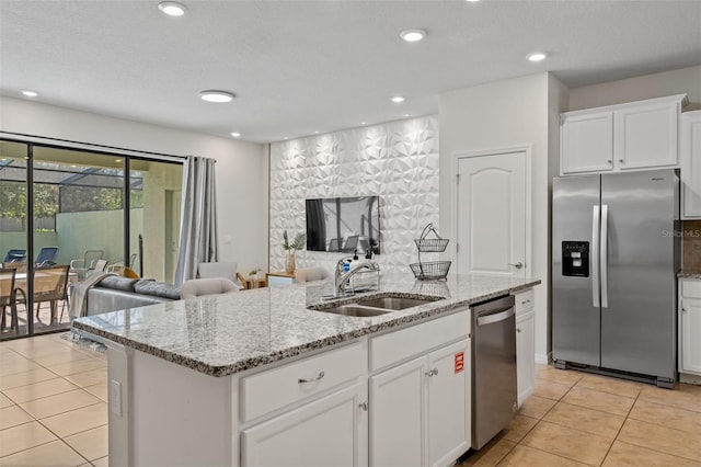 kitchen featuring a center island with sink, light tile patterned floors, stainless steel appliances, open floor plan, and a sink