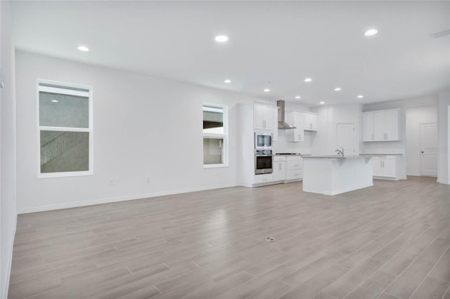 unfurnished living room with sink and light hardwood / wood-style floors