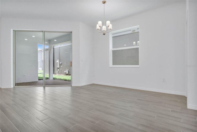 spare room with a notable chandelier and light hardwood / wood-style floors