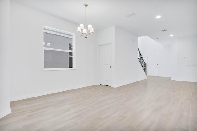 unfurnished room featuring an inviting chandelier and light hardwood / wood-style flooring