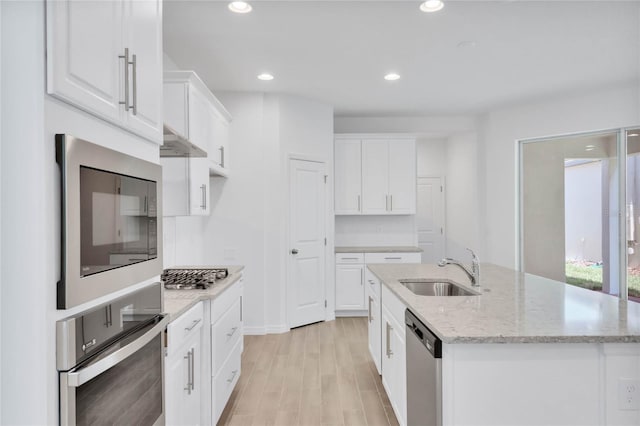 kitchen with stainless steel appliances, sink, a center island with sink, light hardwood / wood-style flooring, and white cabinets