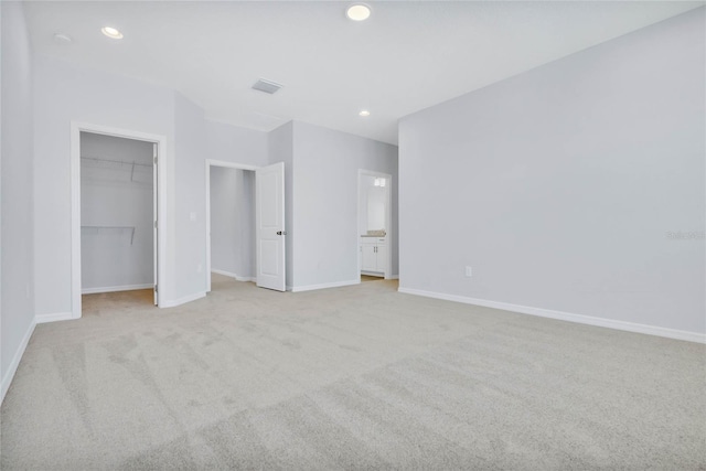 unfurnished bedroom with light carpet, a walk in closet, and a closet