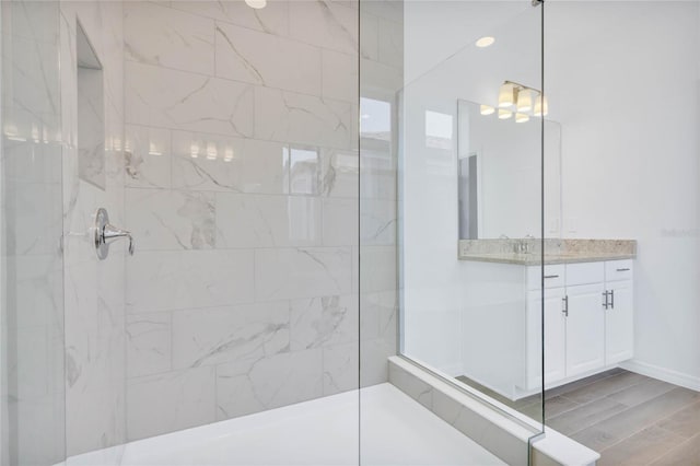 bathroom with a tile shower and vanity