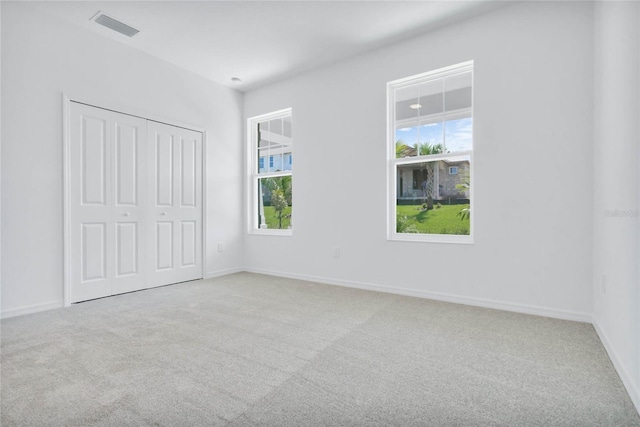 unfurnished bedroom featuring a closet and light colored carpet