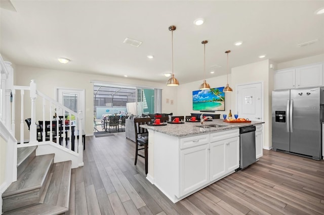 kitchen with white cabinets, pendant lighting, a center island with sink, and appliances with stainless steel finishes