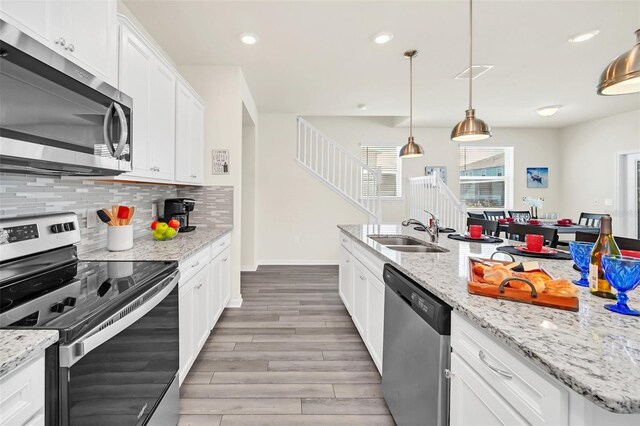 kitchen featuring white cabinets, sink, tasteful backsplash, decorative light fixtures, and stainless steel appliances