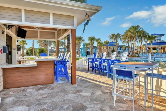 view of patio featuring ceiling fan and a bar