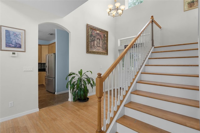 stairway with hardwood / wood-style floors and a chandelier