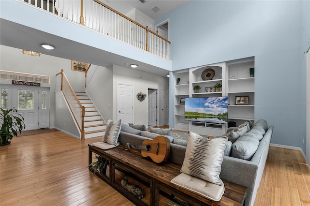 living room featuring hardwood / wood-style flooring and a towering ceiling