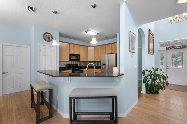 kitchen with pendant lighting, black appliances, a textured ceiling, and light wood-type flooring