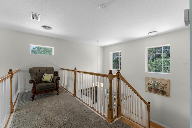 sitting room with carpet flooring, a textured ceiling, and a wealth of natural light