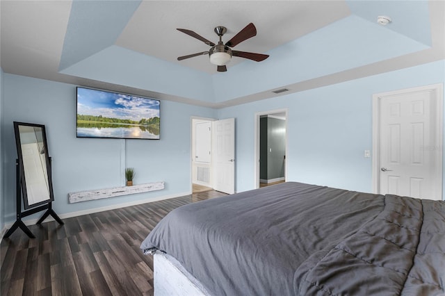 bedroom featuring dark hardwood / wood-style floors, a raised ceiling, and ceiling fan