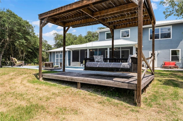 back of property with a deck, a lawn, and a sunroom