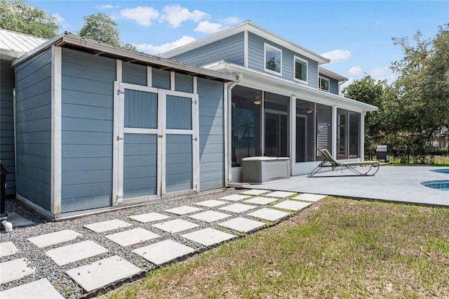 back of property featuring a yard, a patio area, and a sunroom