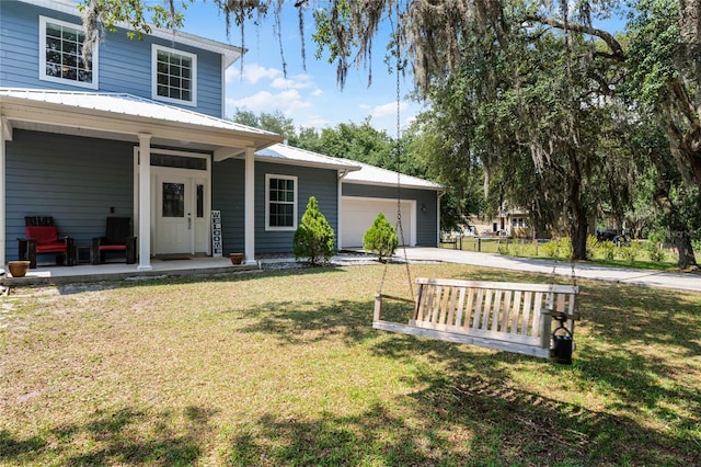 view of front of home featuring covered porch, a garage, and a front yard