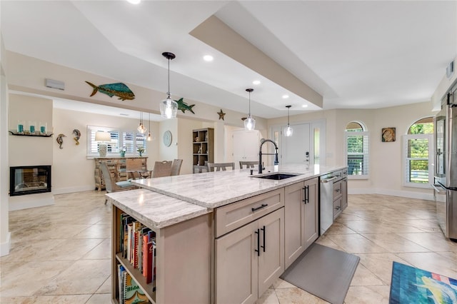 kitchen featuring decorative light fixtures, sink, light stone countertops, a kitchen island with sink, and stainless steel appliances