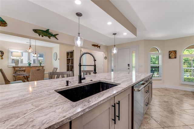 kitchen featuring light stone counters, sink, hanging light fixtures, and plenty of natural light