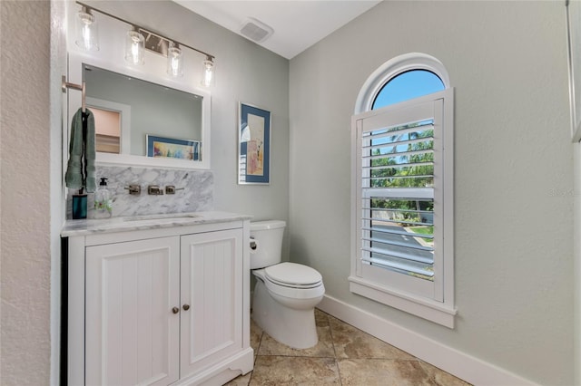 bathroom featuring vanity, toilet, and backsplash