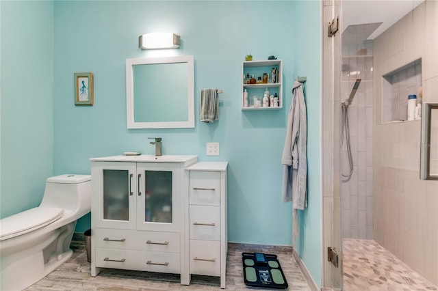 bathroom featuring hardwood / wood-style flooring, toilet, a shower with shower door, and vanity