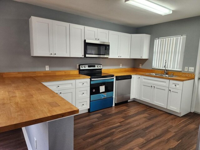 kitchen featuring appliances with stainless steel finishes, white cabinetry, sink, and wood counters