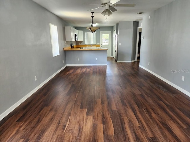 unfurnished living room featuring ceiling fan and dark hardwood / wood-style flooring